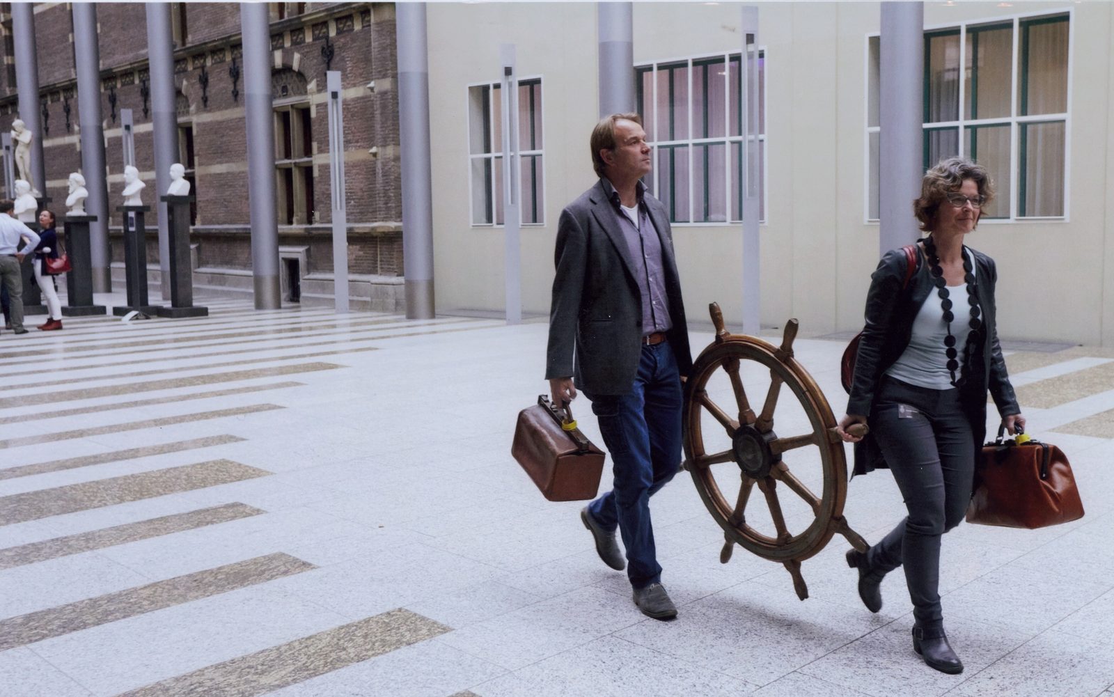 Pascale en Stan dragen het scheepsroer door de hal van de Tweede Kamer